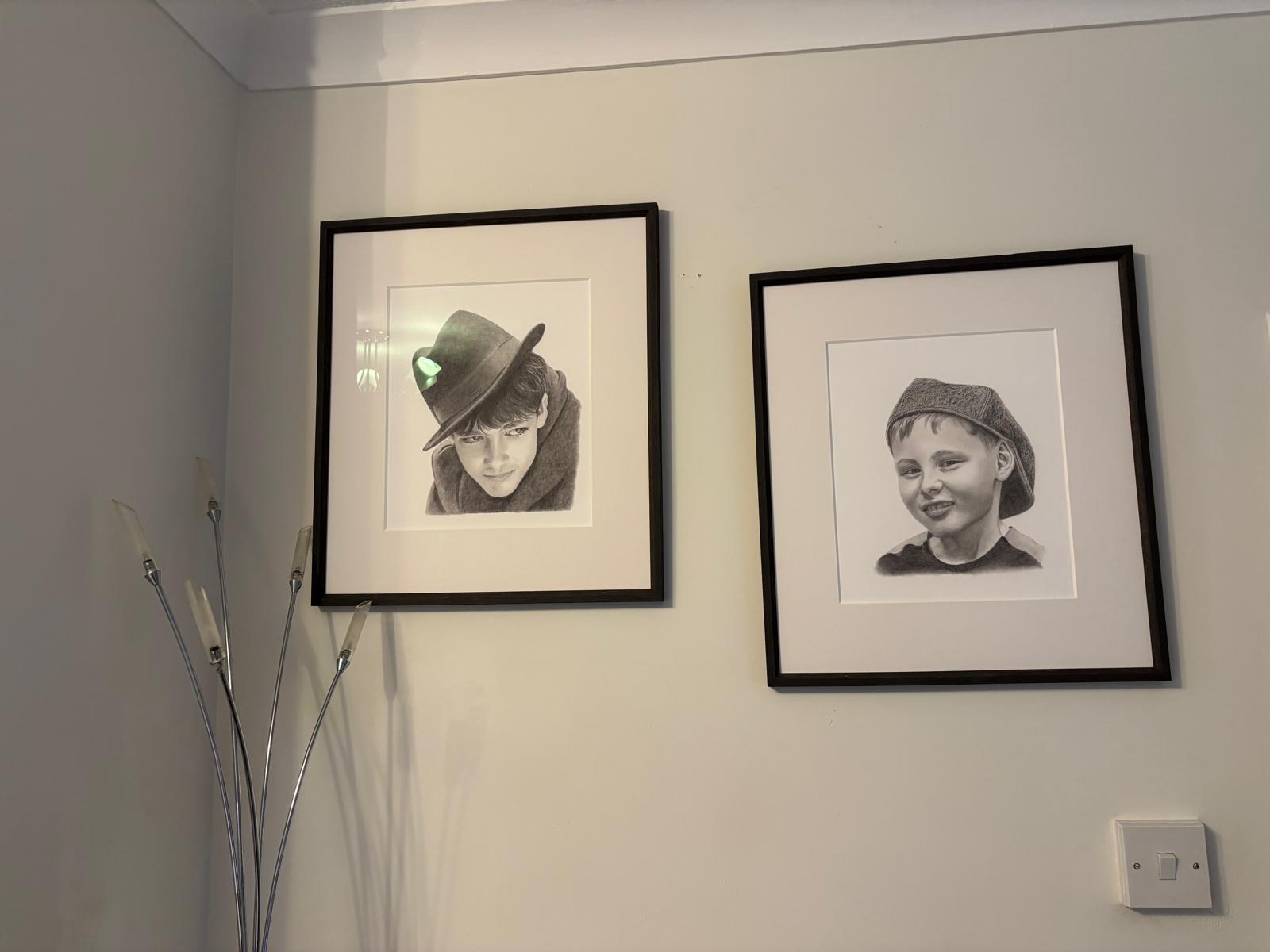 Two detailed pencil portrait drawings of children in matching black frames