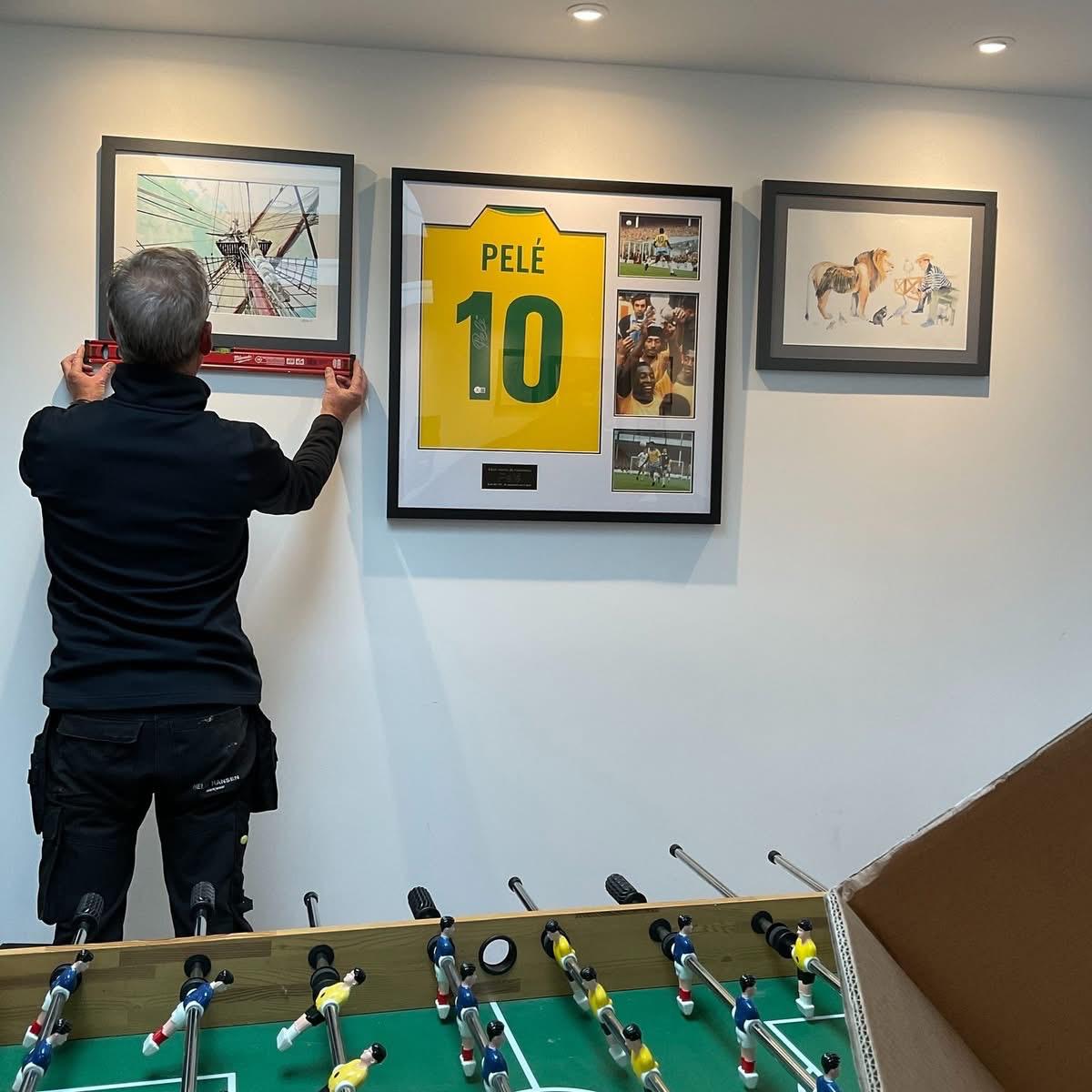 Hall of Frame installing a framed Pel&eacute; signed shirt in a client's home